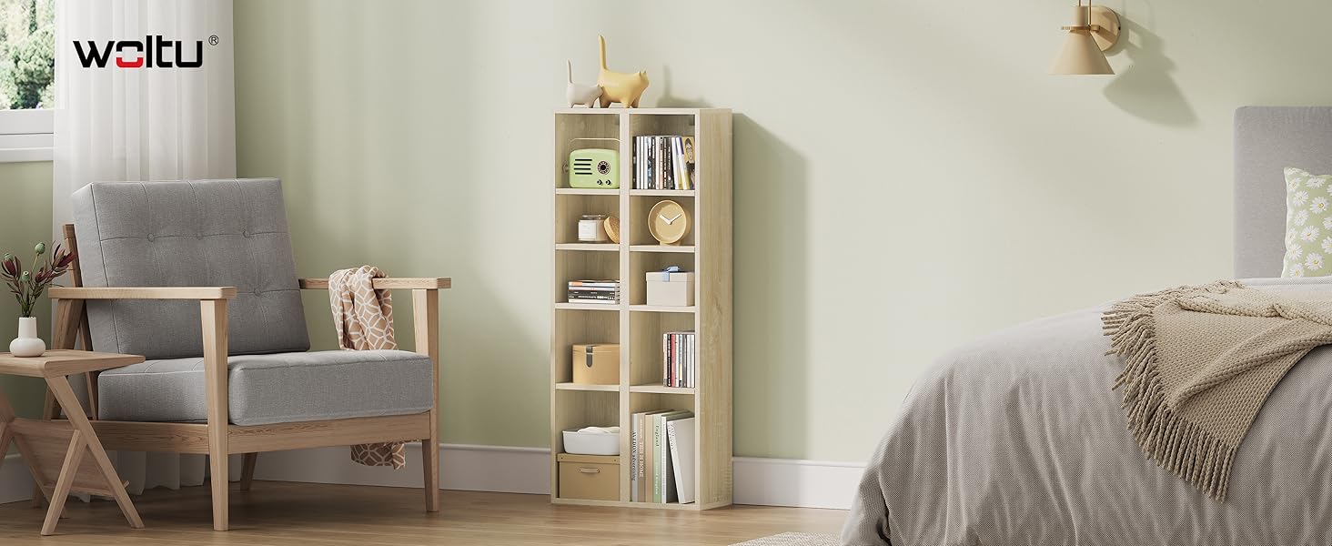 Libreria in legno con più scomparti in una camera da letto, che mostra lo spazio per libri e oggetti decorativi. Poltrona e letto grigi