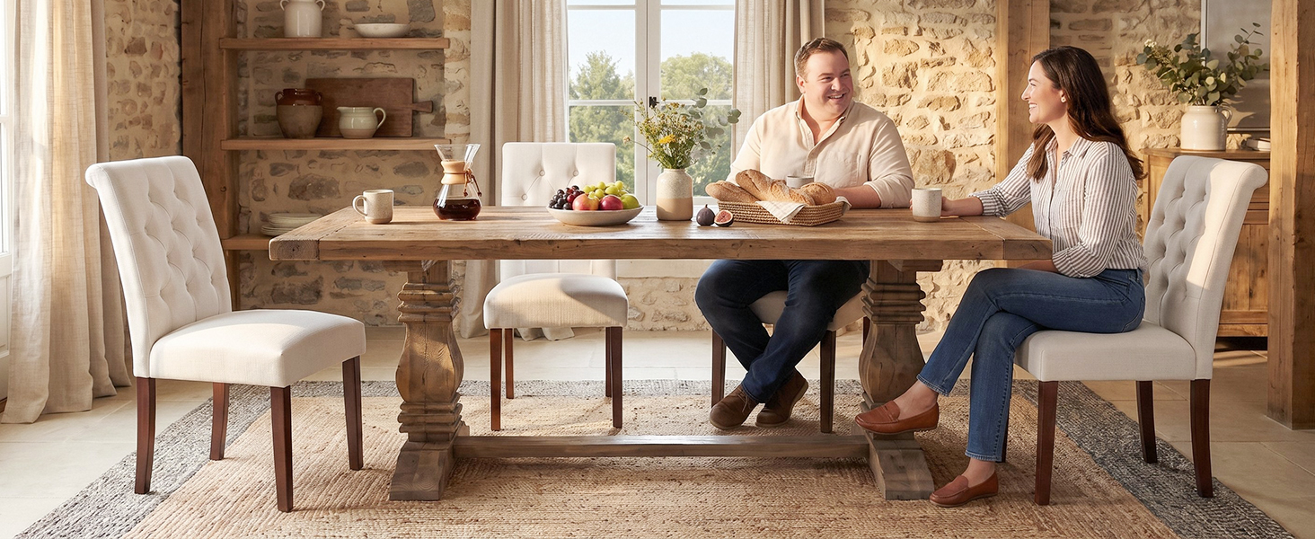 Esstisch aus Holz mit vier gepolsterten Stühlen in einer warmen, traditionellen Inneneinrichtung. Zwei Personen sitzen an einem Tisch mit Gedeck und Blumen, die in den Regalen im Hintergrund sichtbar sind.