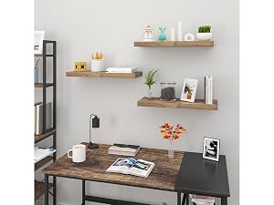 Home office setup with dark wood desk, floating wooden shelves displaying decorative items, and minimal wall decor against light gray wall.