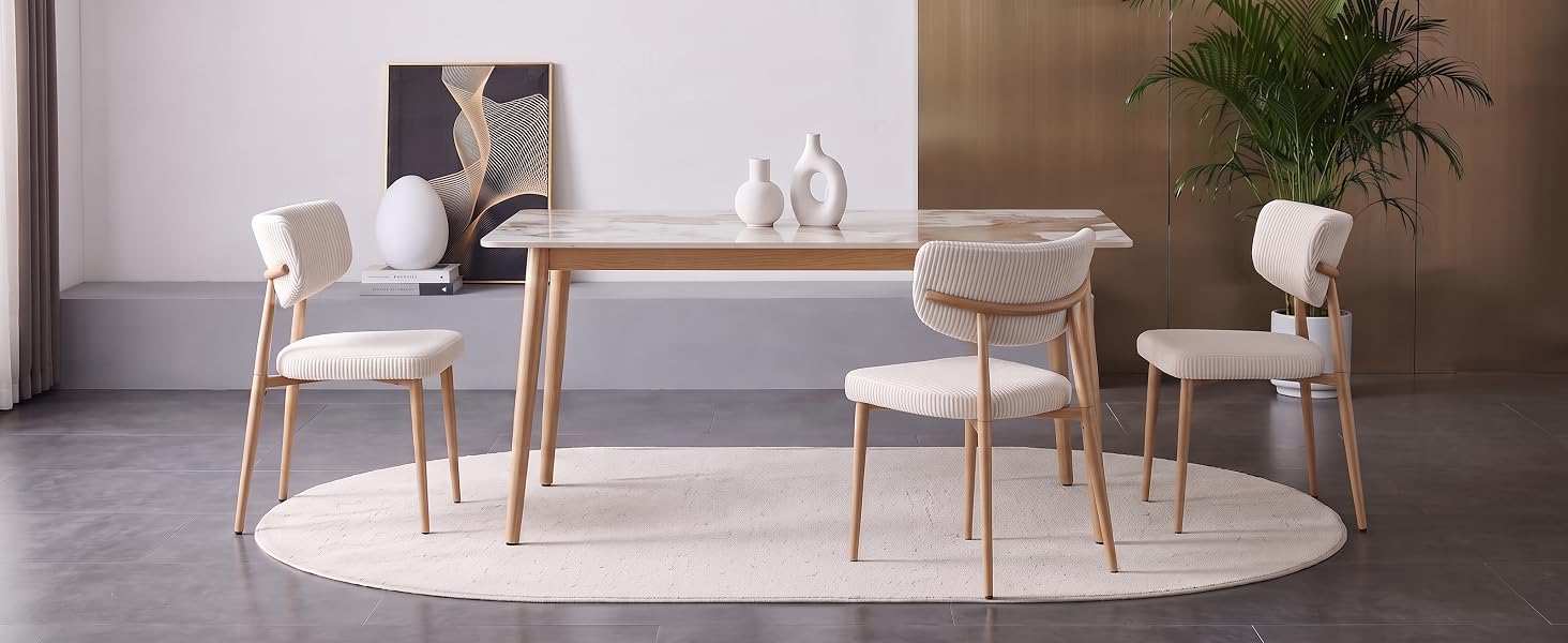 Moderne Essgruppe mit hellem Holztisch und vier Stühlen mit cremefarbener Polsterung auf einem runden weißen Teppich in einem minimalistischen Zimmer mit neutralem Dekor.