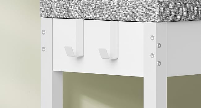 Primo piano del trattamento della finestra che mostra mantovana grigia testurizzata con paralume a rullo bianco e due supporti in tessuto decorativo bianco montati su telaio bianco.