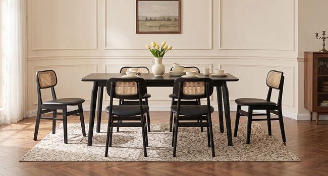 Table à manger noire moderne avec quatre chaises noires dans une pièce intérieure minimaliste avec des murs blancs, un manteau de cheminée orné et un tapis.