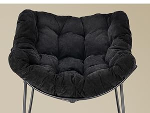 Cojín acolchado negro para silla Papasan con botones profundos y bordes enrollados, que se muestra sobre una estructura de metal gris sobre un fondo beige.