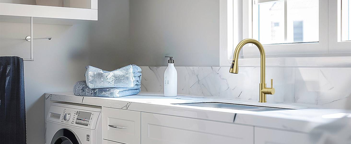 Modern laundry room with marble countertop, gold faucet, and white cabinets. Washing machine visible on left side.