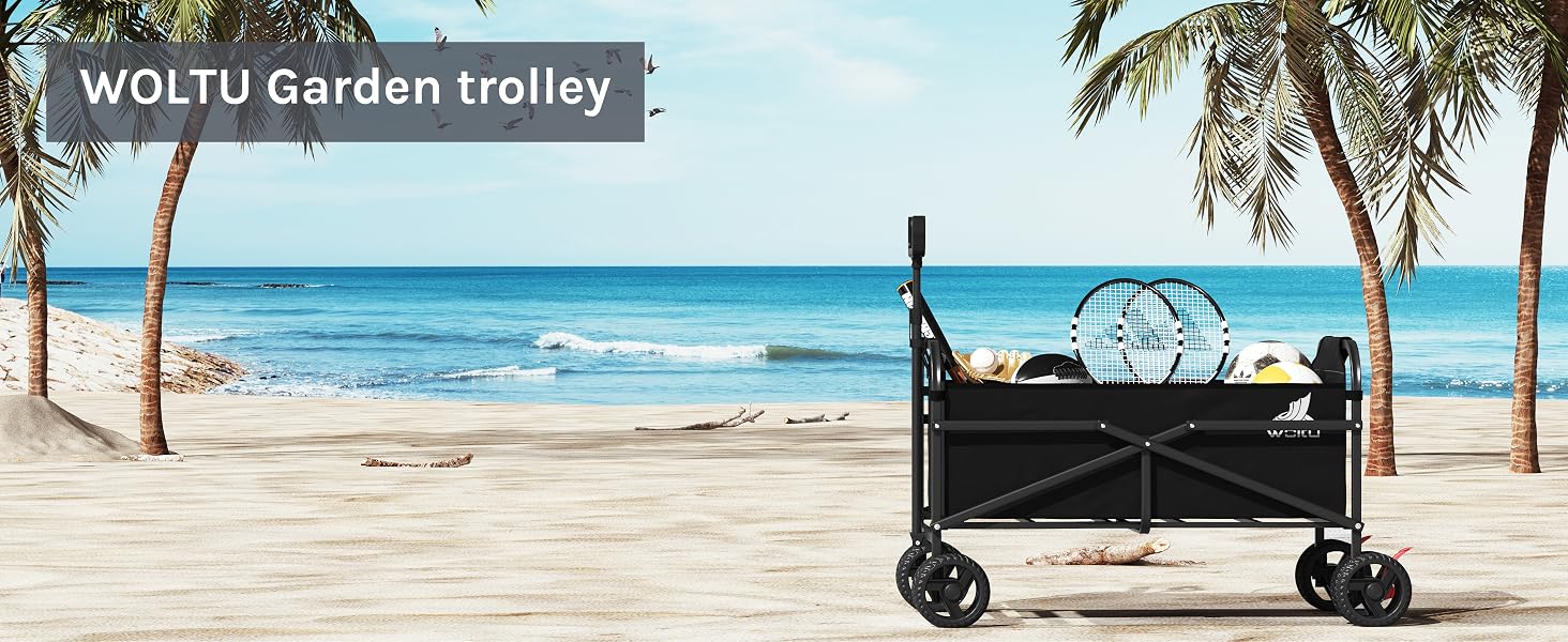 Collapsible black garden trolley on a beach between palm trees. Four-wheeled cart with fabric sides and handle for pulling. Ocean and sky visible in background.