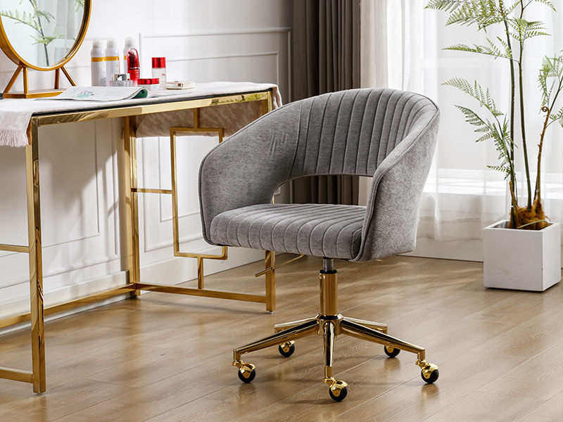 en velours gris avec capitonnage à canaux verticaux, dossier incurvé et base dorée à roulettes. Situé près d'un bureau à cadre doré dans un décor intérieur moderne