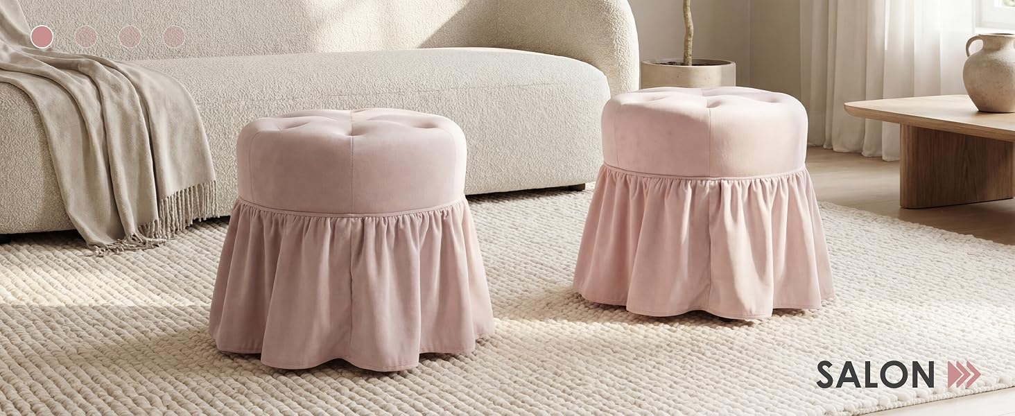 Le texte indique « SALON » en bas à droite. L'image montre deux poufs ou poufs en tissu plissé rose avec des détails de jupe froncés placés sur un tapis beige clair dans un salon moderne et neutre avec des meubles rembourrés crème.