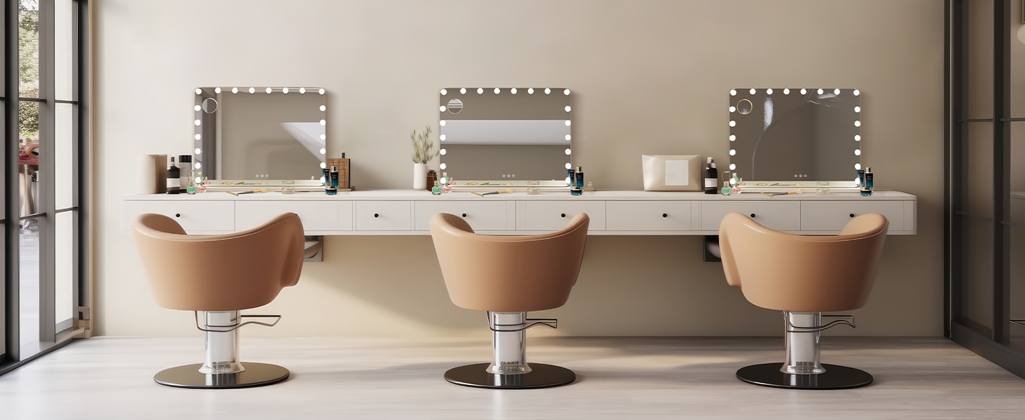 Professional salon setup with three tan leather styling chairs and illuminated vanity mirrors mounted on white wall with storage drawers underneath.
