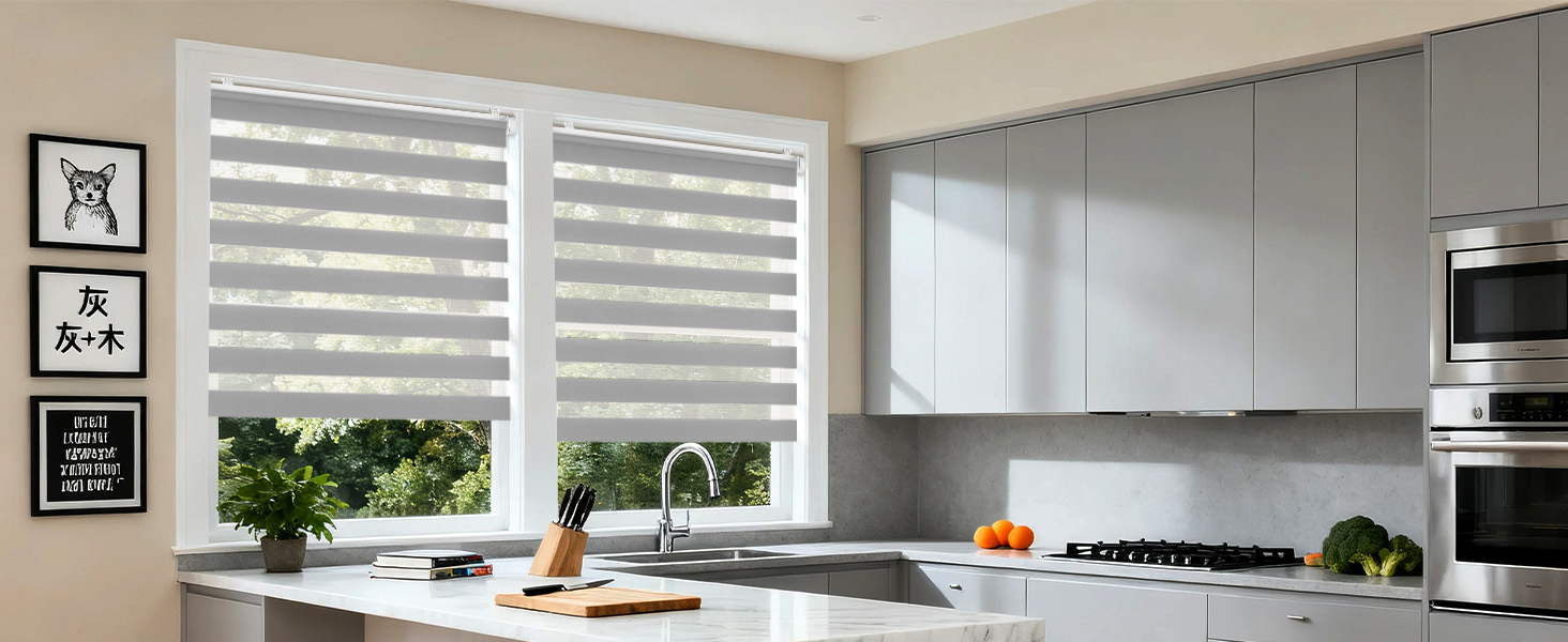 Intérieur de cuisine moderne avec stores zébrés blancs et doubles volets roulants sur les fenêtres, avec armoires et plans de travail blancs avec un décor minimal.