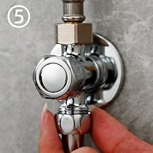 Válvula de ángulo o de parada cromada con perilla de control circular, montada en una pared de concreto texturizado o gris