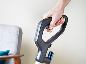 Handstaubsauger mit ergonomischem Griff und schmaler Düse, demonstriert beim Reinigen eines hellen Sofas oder