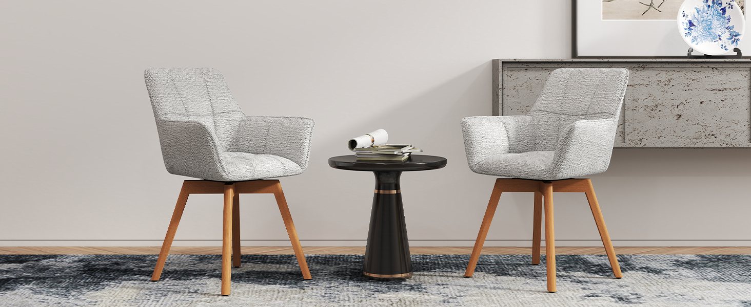 Deux chaises d'appoint rembourrées beiges avec pieds en bois positionnées autour d'une petite table d'appoint ronde noire contre un mur gris clair.