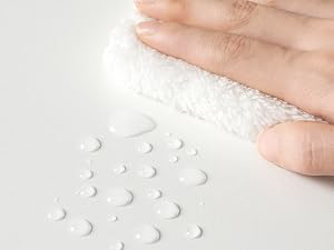 Primer plano del dedo que toca la superficie texturizada blanca que muestra gotas de agua y detalles de la textura de la superficie.