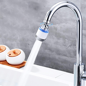 Chrome kitchen faucet with attached water filter attachment showing water flow, mounted on grey counter surface.