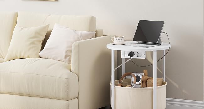 Mesa auxiliar blanca con estante abierto colocada junto a un sillón de color crema en una sala de estar con un portátil en la parte superior.
