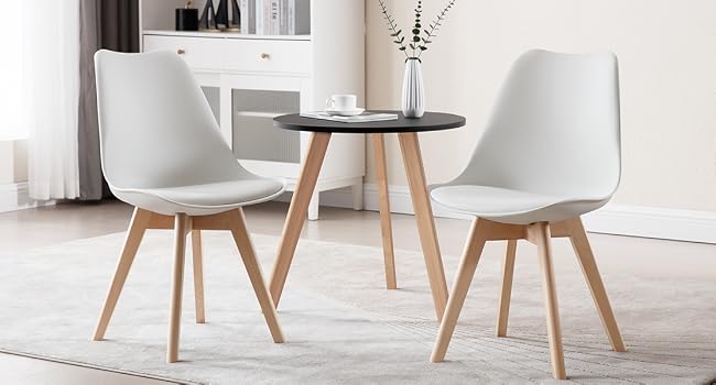Modern dining set with round wooden table and three white chairs. Minimalist design with wooden chair legs in a bright interior setting.