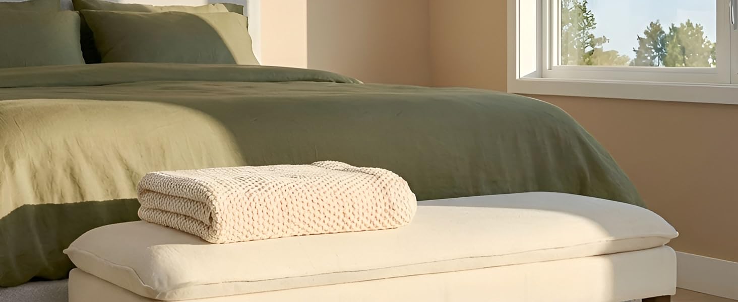 Plan intérieur de coussins ou d'oreillers beiges posés sur ce qui semble être un canapé ou une surface assise, avec de la lumière naturelle provenant d'une fenêtre.