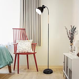 Moderne Stehleuchte mit verstellbarem schwarzem Metallschirm und schlankem Standfuß. In der Nähe eines roten Holzstuhls und eines weißen Schranks in einer minimalistischen Raumumgebung positioniert.