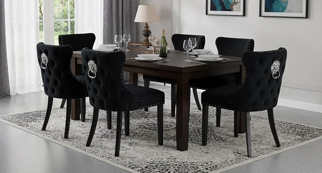 Interno moderno della sala da pranzo con sedie imbottite nere attorno al tavolo in legno scuro, posizionate su un tappeto a motivi geometrici in uno spazio luminoso con pareti bianche.