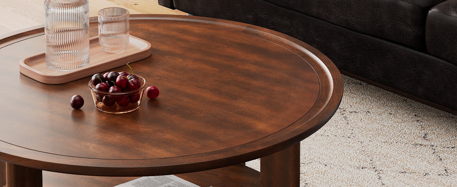 Circular wooden coffee table with raised edge. Surface holds glassware and small bowl of cherries. Part of dark sofa visible, table on light carpet.