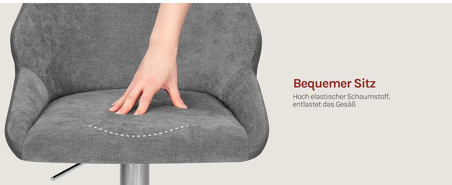 Der Text lautet „Ergonomic Slip“ und scheint Produktdetails anzuzeigen. Die Hand liegt auf einem Kissen oder Polster aus grauem, strukturiertem Stoff vor beigem Hintergrund.