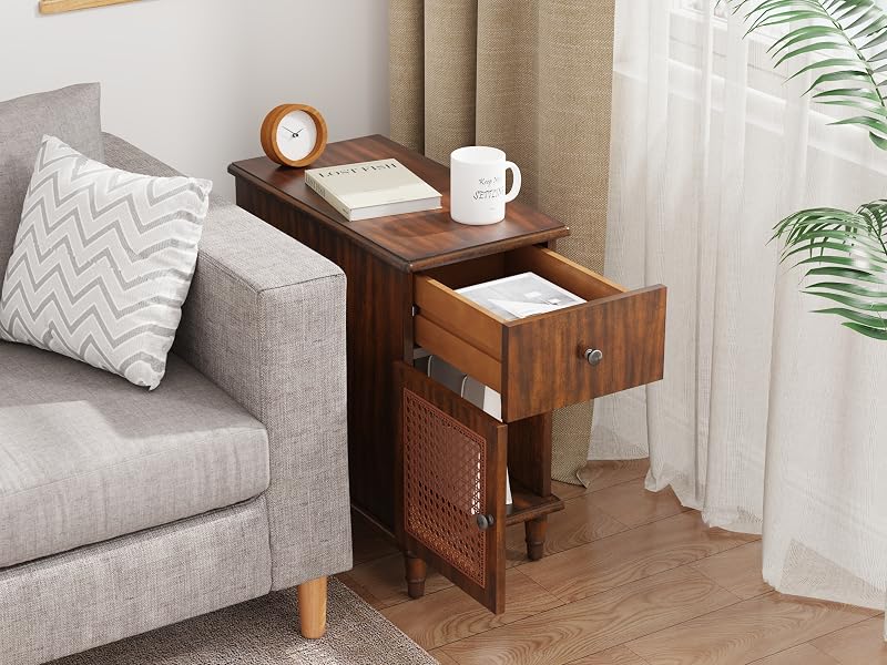 Wooden side table with drawer and cabinet, placed next to gray sofa. Table top holds clock, notebook, and mug. Drawer partially open, revealing storage space.