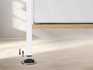 Primo piano di una gamba regolabile nera per mobili con frecce su e giù. Sopra è visibile una superficie rivestita in tessuto bianco, che suggerisce
