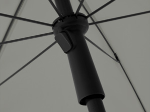 Close-up of black umbrella shaft and mechanism against light background. Central rod and ribbed structure partially visible.