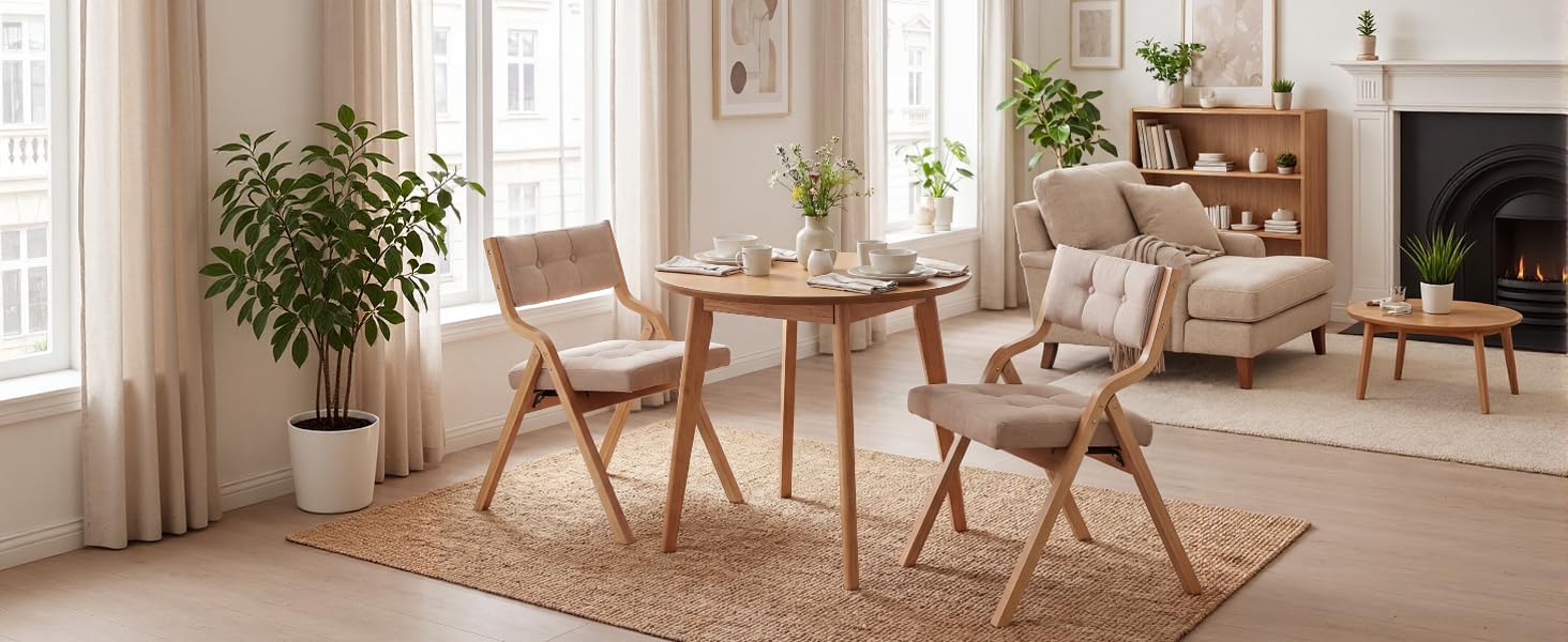 Minimalist dining area with round wooden table, two chairs, indoor plants, and natural lighting. Room features neutral tones and modern Scandinavian-style furniture.