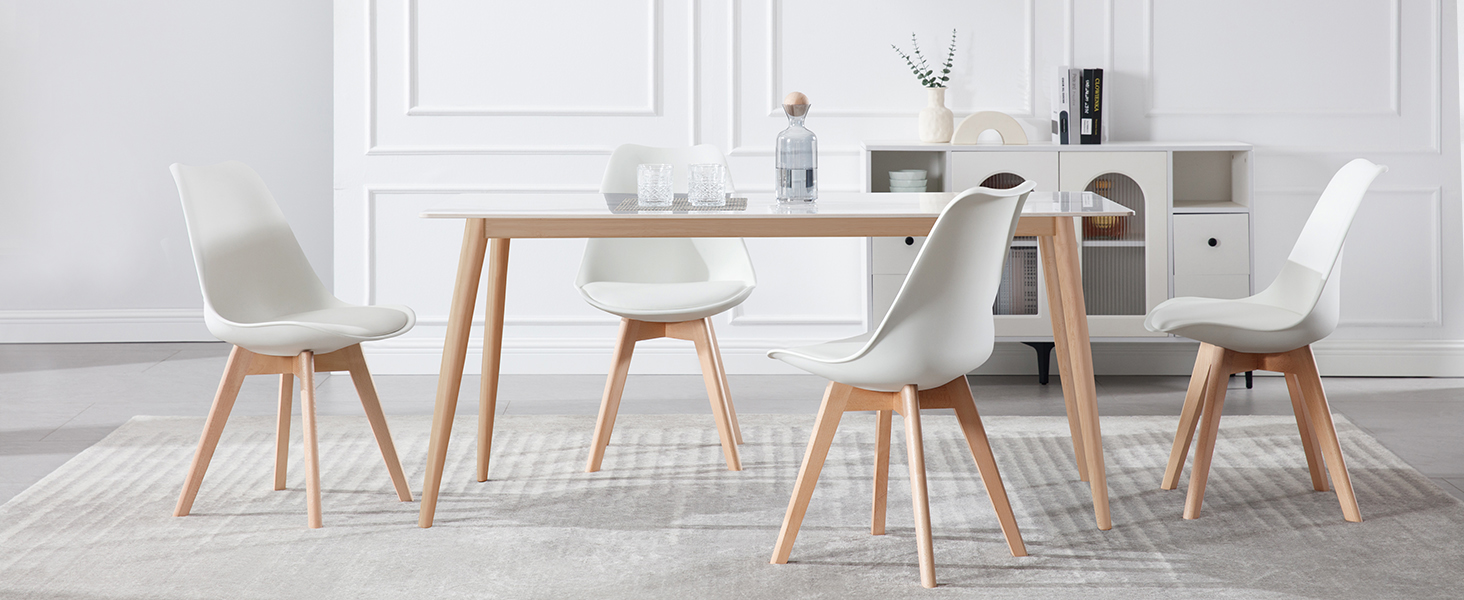 Juego de comedor moderno con mesa de madera y cuatro sillas blancas. Las sillas tienen asientos moldeados y patas de madera. Aparador blanco visible en el fondo