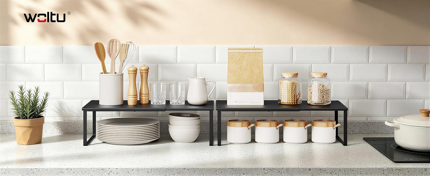 El texto dice «WCELU». Expositor de cocina que muestra tarros y recipientes de cerámica blanca con estantes organizadores de metal que contienen cosméticos y artículos de decoración del hogar sobre la encimera.