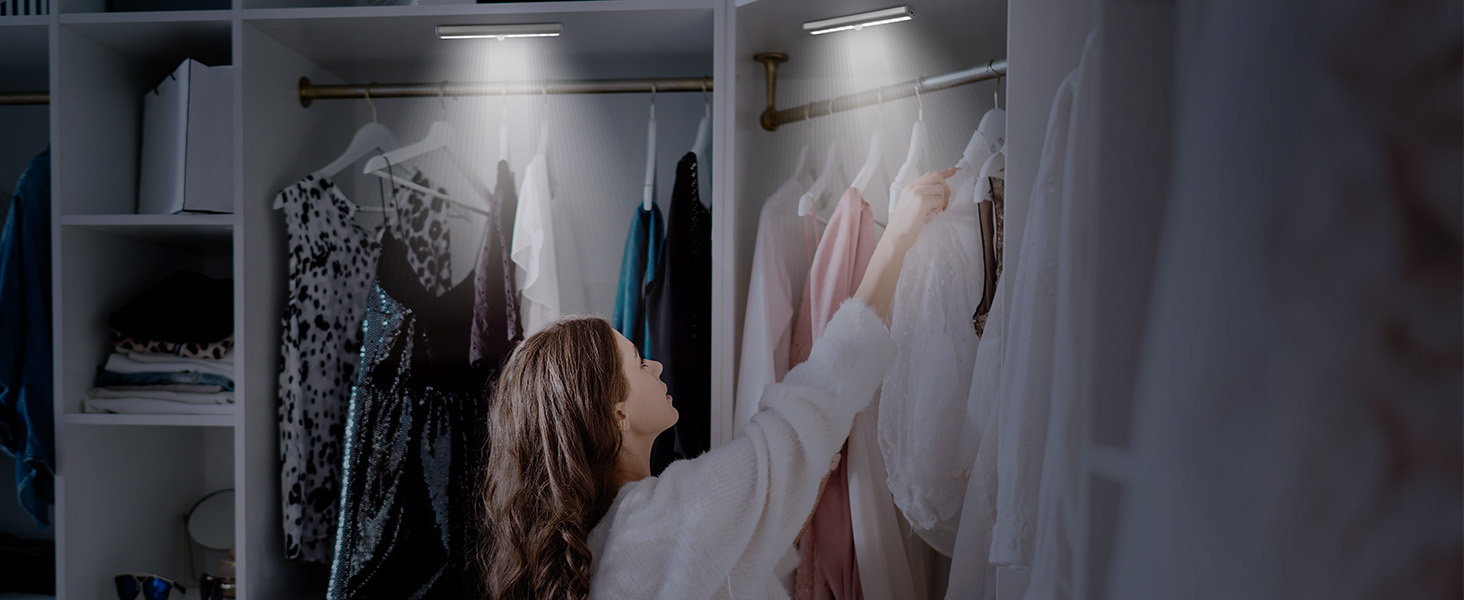Walk-in closet interior featuring organized clothing racks with garments in light and dark colors, and built-in white shelving units.