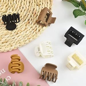 Assortment of small hair clips in various colors and designs, including claw clips and banana clips, displayed on a woven surface.