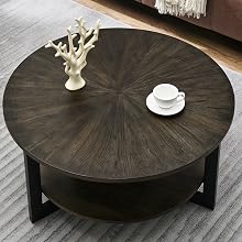Round dark wood coffee table with radial grain pattern, lower shelf, and black metal legs. Decorated with white coral sculpture and coffee cup.