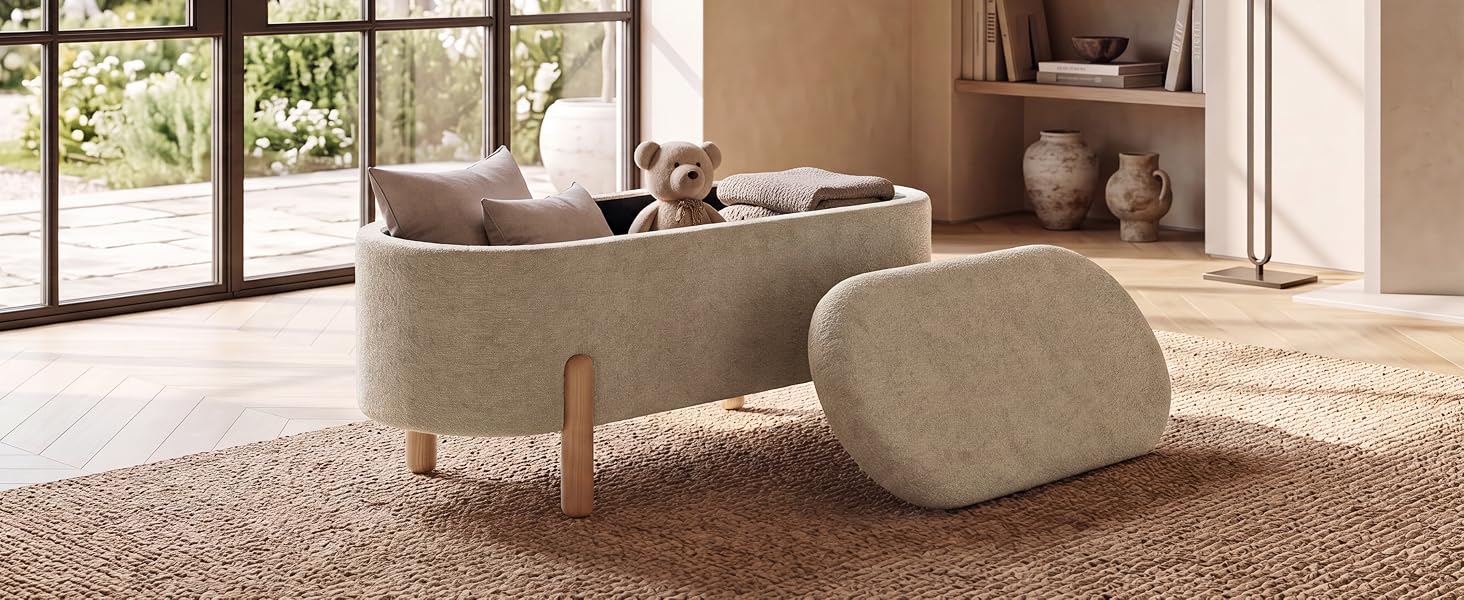 L'intérieur du salon moderne comprend un grand canapé rembourré beige, un pouf ottoman cylindrique, des meubles de rangement en bois, des plantes en pot et un parquet en bois franc dans des tons neutres avec des portes vitrées visibles.