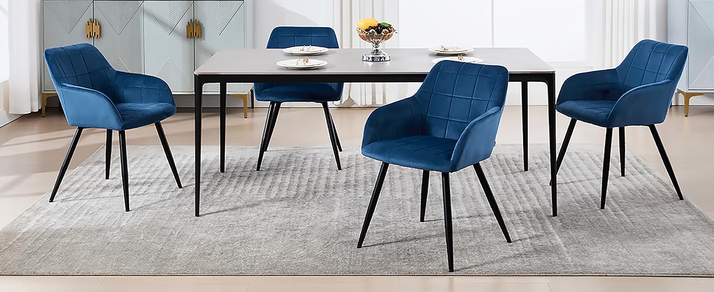 con cuatro sillas tapizadas en azul marino con respaldos curvos alrededor de una mesa de comedor negra sobre una alfombra gris