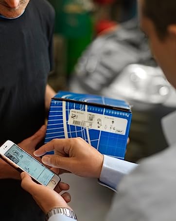 Close-up of hands holding mobile phone and blue folder during what appears to be a business interaction.