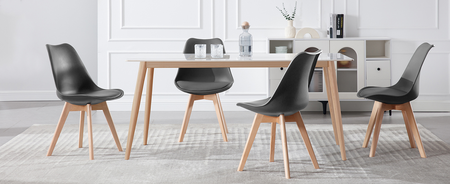 con mesa de madera con patas con acabado natural y cuatro sillas moldeadas negras con patas de madera a juego en una habitación luminosa.