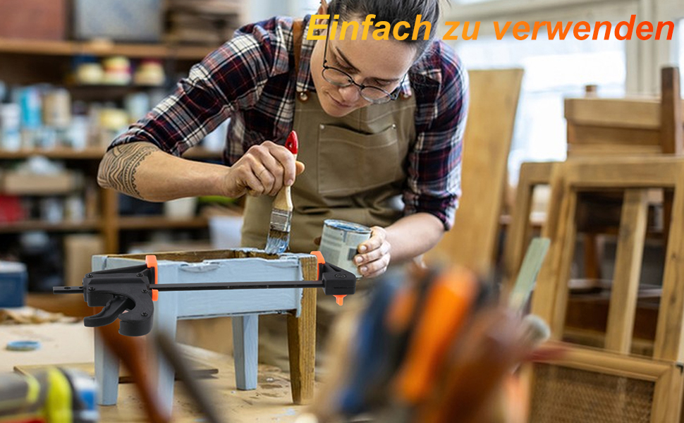 Artisan en tablier et chemise à carreaux travaillant sur un établi, appliquant soigneusement de la peinture ou une finition