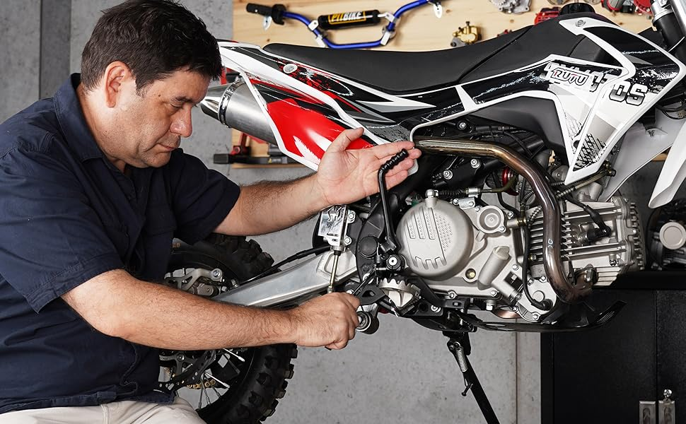Mechanic performing maintenance work on a motorcycle engine, focusing on the internal mechanical components.