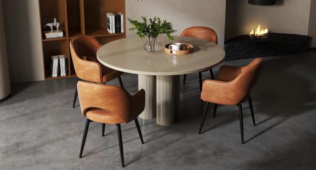 Modern dining set with round cream table and four orange upholstered chairs. Table has fluted base. Room features built-in shelving and fireplace.