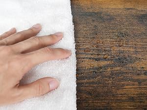Confronto tra la trama dell'asciugamano bianco e la superficie in legno. Il morbido tessuto in asciugamano che tocca la mano contrasta con le venature ruvide e invecchiate del legno