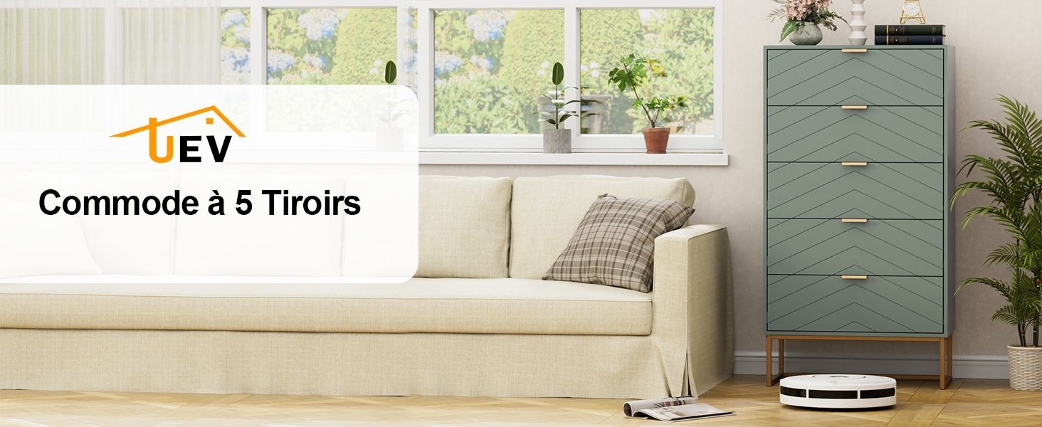 Le texte indique « Commode à 5 Tiroirs » et « UEV ». Commode gris-bleu moderne à cinq tiroirs présentée dans un cadre domestique avec des murs blancs, des plantes en pot et un aspirateur robotique visible.
