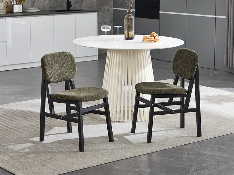 Modern dining set featuring round white table with pleated base and two olive green chairs with black frames in grey-tiled kitchen setting.