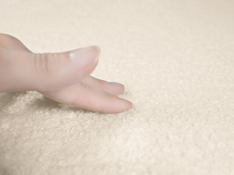 Close-up textural shot of a cream or moisturizer product with smooth, pearl-like finish on light beige background.