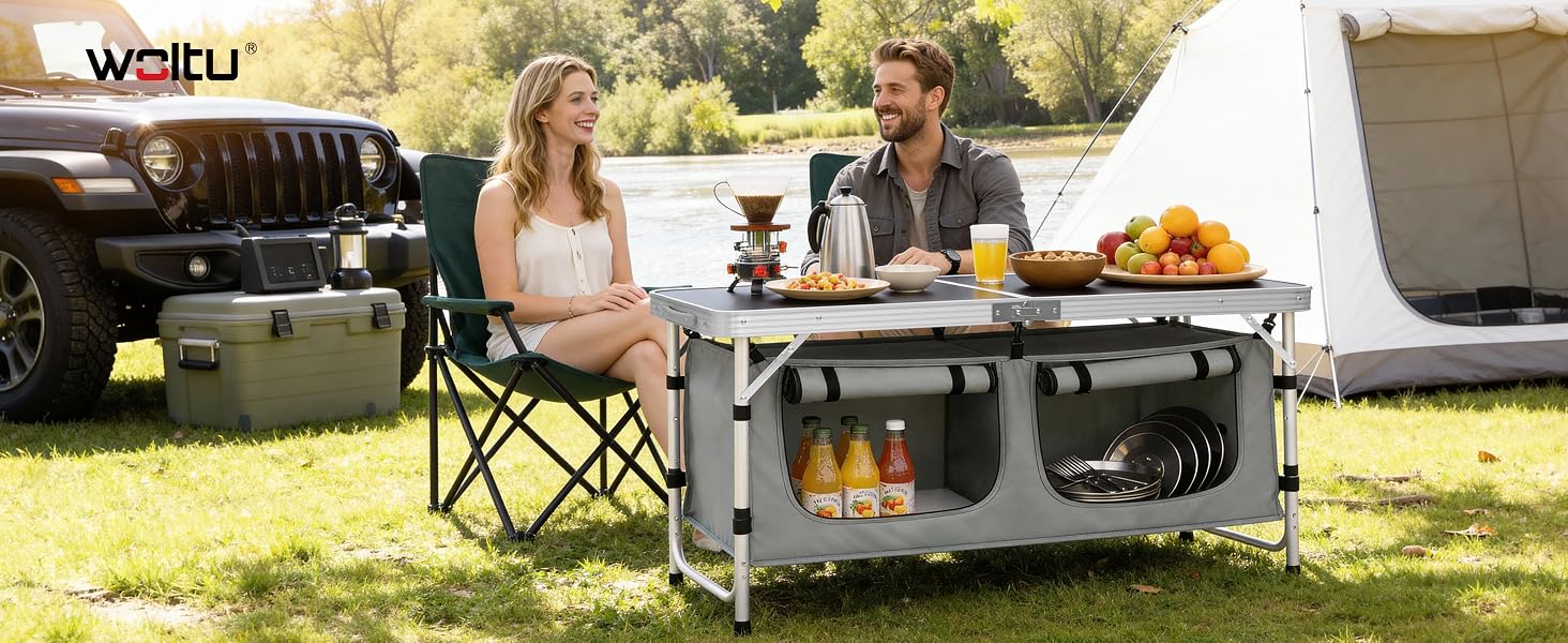 Text reads: 'WALTU' Portable outdoor camping table setup with storage compartments, shown with people dining outdoors next to a Jeep vehicle