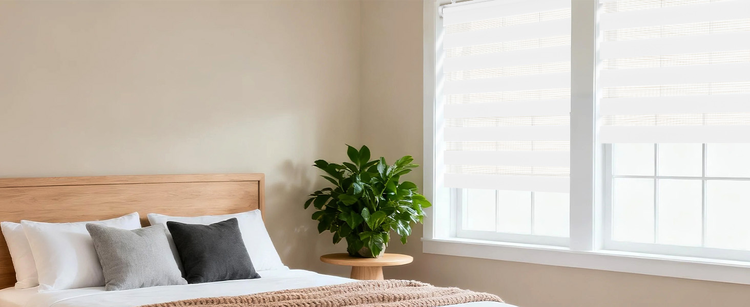 Intérieur de chambre moderne et minimaliste avec cadre de lit en bois, literie blanche, plante verte et grande fenêtre laissant entrer la lumière naturelle.