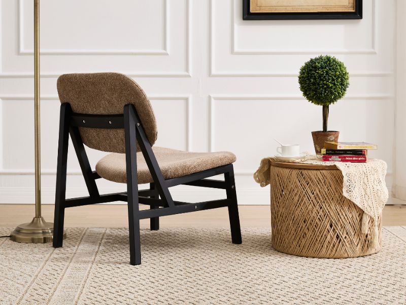 Intérieur de salon moderne avec chaise noire à profil bas avec revêtement marron, positionnée près d'un topiaire décoratif sur une base en bois.
