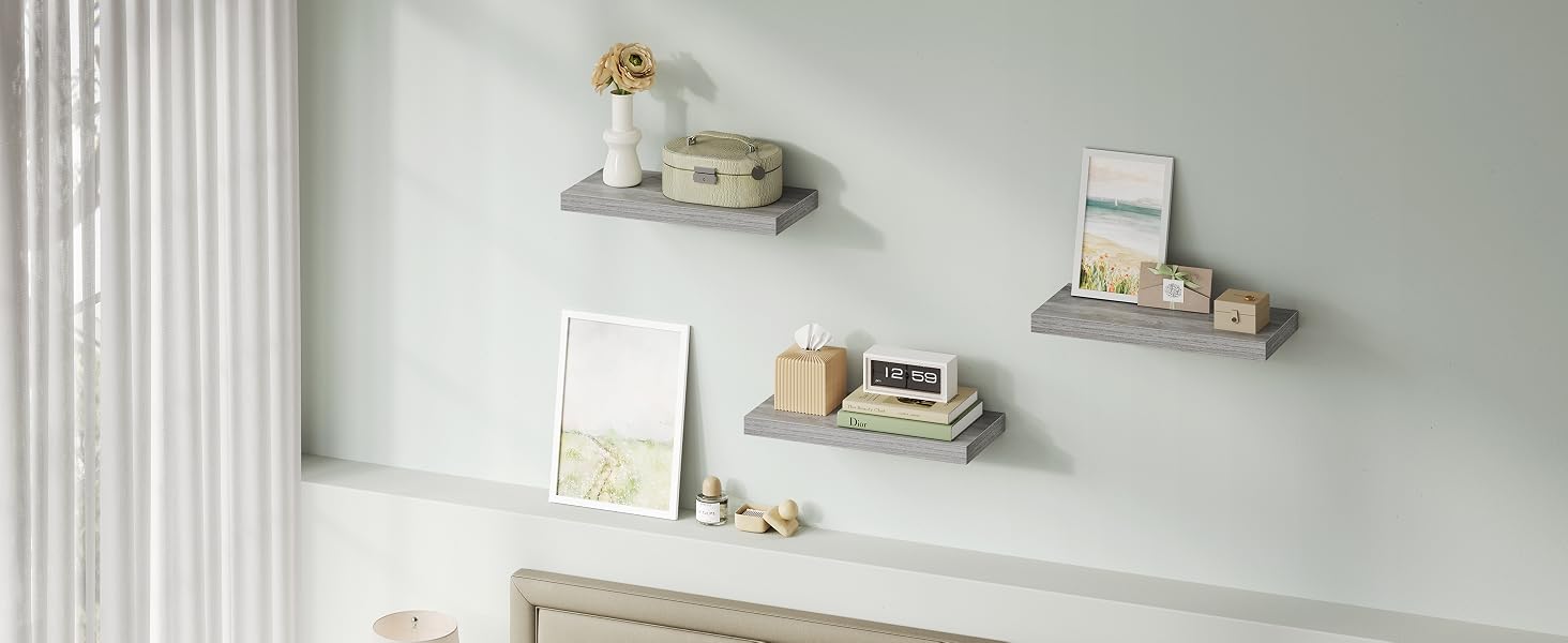 Disposizione minimalista di scaffali da parete con piccoli ripiani galleggianti con oggetti decorativi e opere d'arte contro una parete grigio chiaro.
