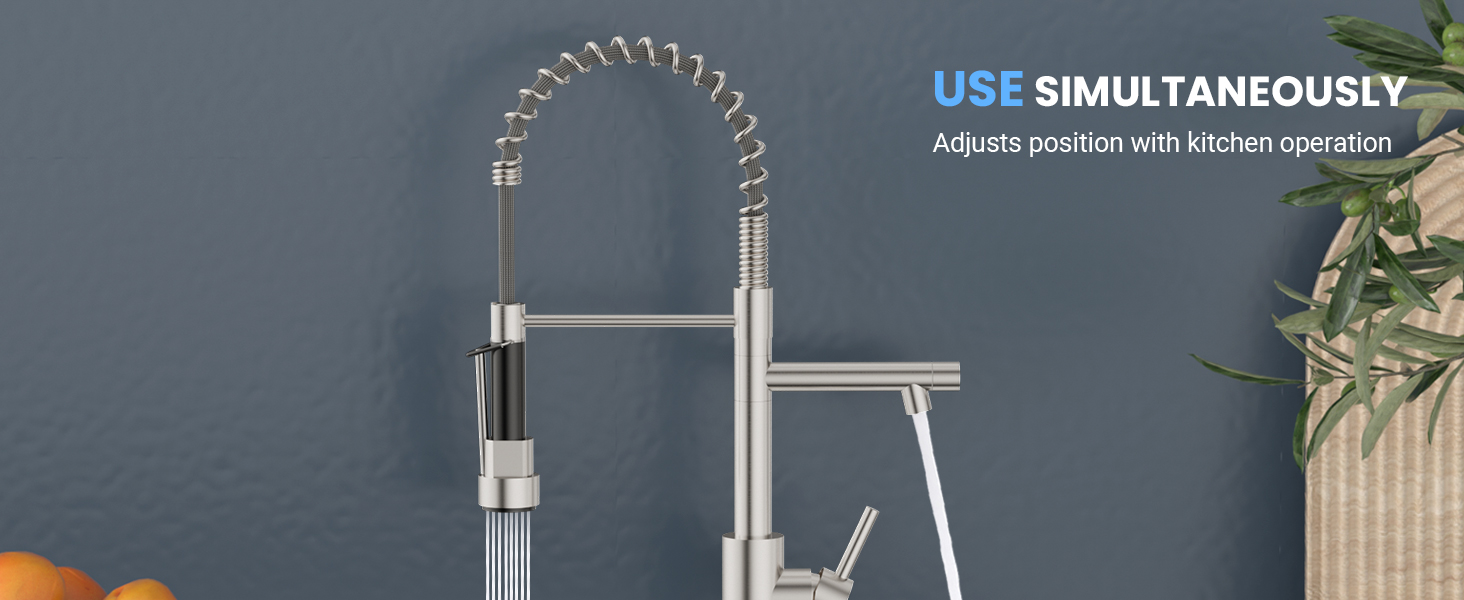Modern kitchen faucet with flexible coiled neck and sleek metal finish, mounted on a dark countertop against a blue wall.